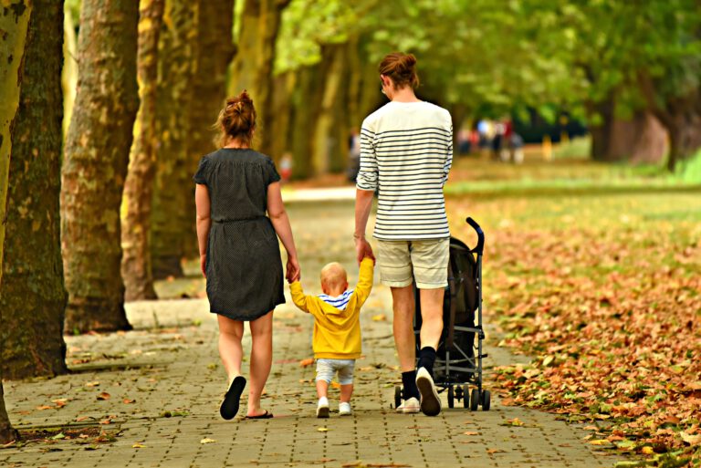 Familie mit Kind und Kinderwagen beim Spaziergang im Park
